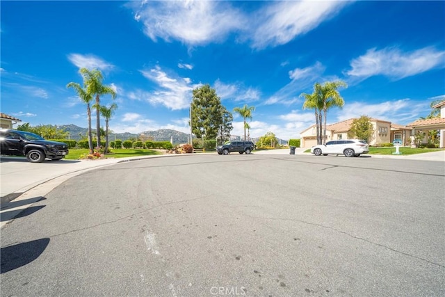 view of street with a mountain view, sidewalks, curbs, and a residential view