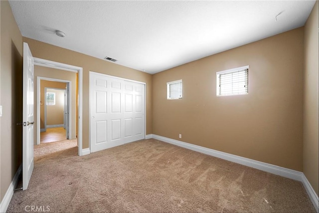 unfurnished bedroom featuring a closet, carpet flooring, visible vents, and baseboards