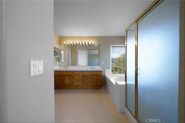 full bathroom with a sink, a textured wall, double vanity, a stall shower, and a garden tub