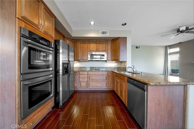 kitchen featuring a sink, dark wood-style flooring, visible vents, light stone countertops, and appliances with stainless steel finishes