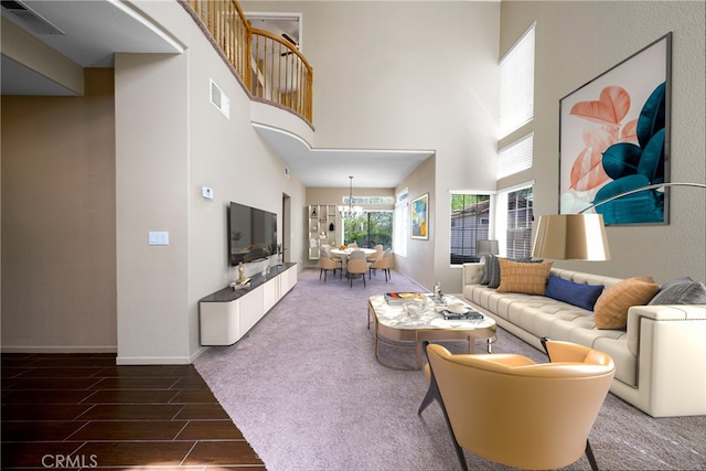 living room with a high ceiling, wood finished floors, a chandelier, and visible vents