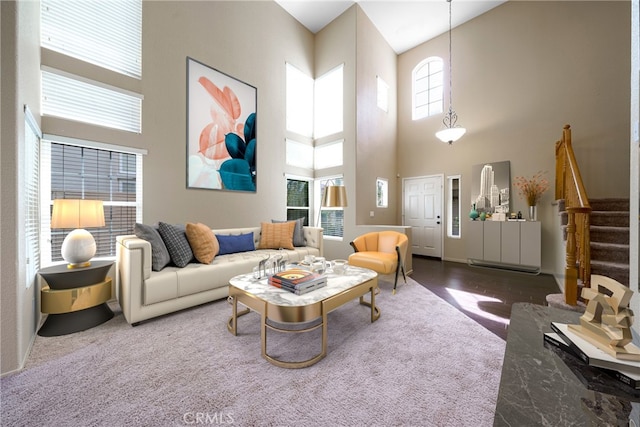 carpeted living room featuring a towering ceiling and stairway