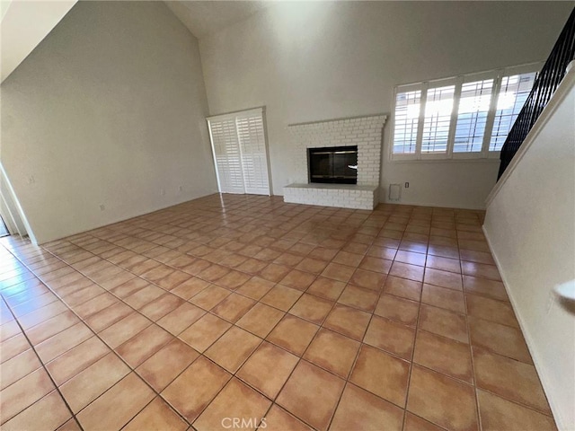 19229 Pine Way, Apple Valley, CA 92308 - unfurnished living room featuring light tile patterned floors, high vaulted ceiling, and a brick fireplace