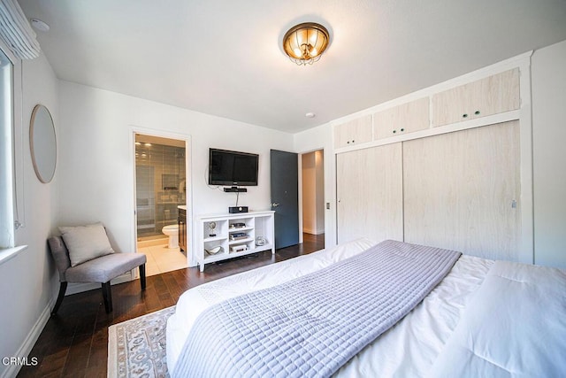 bedroom featuring a closet, ensuite bathroom, baseboards, and dark wood finished floors