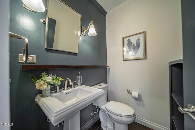 bathroom featuring a sink, ornamental molding, toilet, and baseboards
