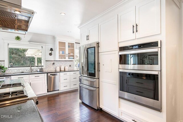kitchen featuring glass insert cabinets, white cabinetry, dark wood finished floors, stainless steel appliances, and decorative backsplash