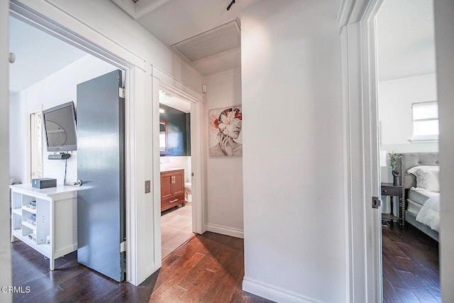 hall featuring dark wood-style floors, baseboards, and visible vents