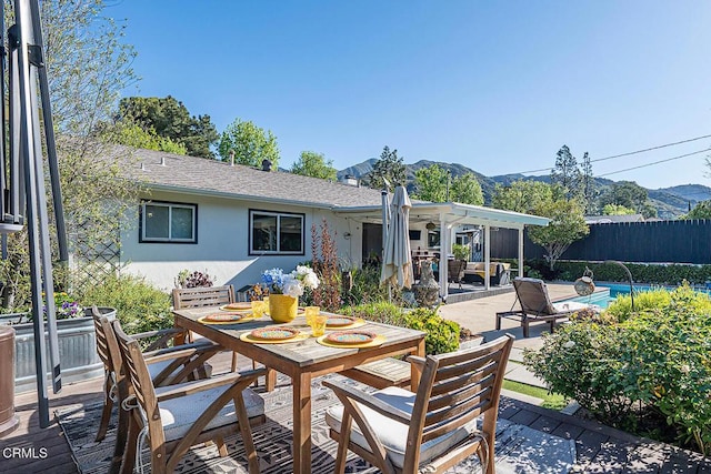 view of patio / terrace with outdoor dining space, a mountain view, fence, and a fenced in pool