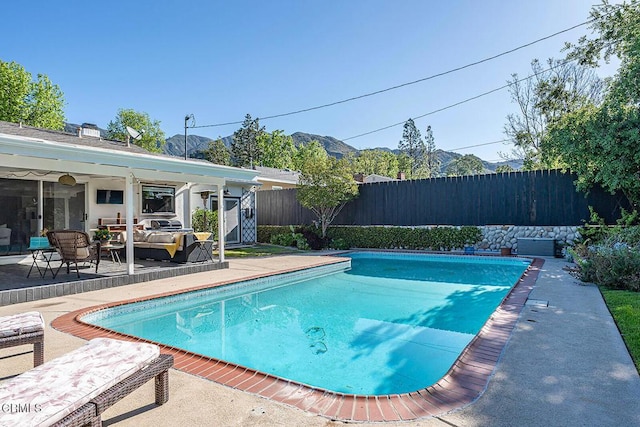 view of swimming pool featuring a mountain view, a patio area, a fenced in pool, and fence