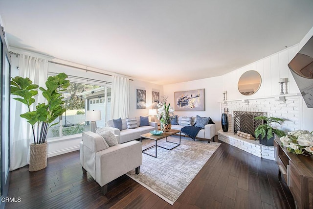 living room featuring a brick fireplace and dark wood finished floors