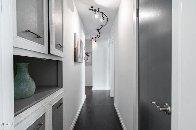 corridor with rail lighting, baseboards, and dark wood finished floors