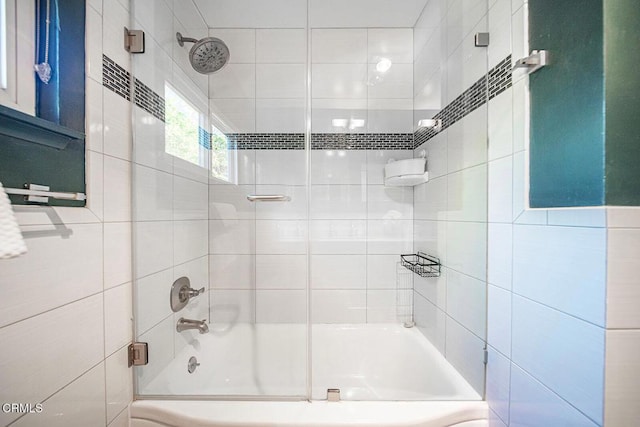 bathroom with shower / bath combination with glass door and tile walls