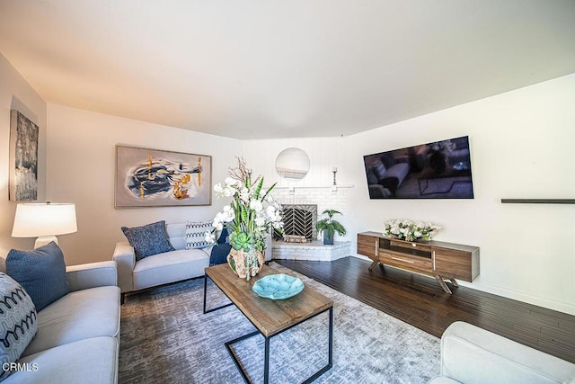 living room featuring a fireplace, baseboards, and wood finished floors