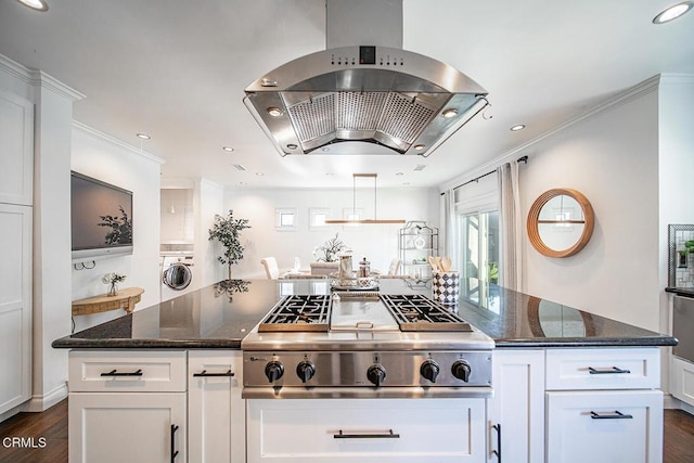 kitchen featuring dark wood-style flooring, washer / clothes dryer, stainless steel gas stovetop, and wall chimney exhaust hood