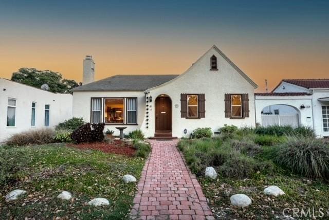 view of front of property featuring a chimney and stucco siding