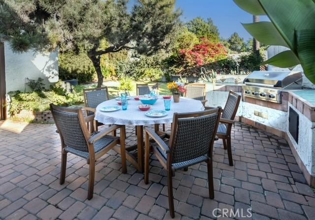 view of patio / terrace featuring exterior kitchen, outdoor dining area, and a grill