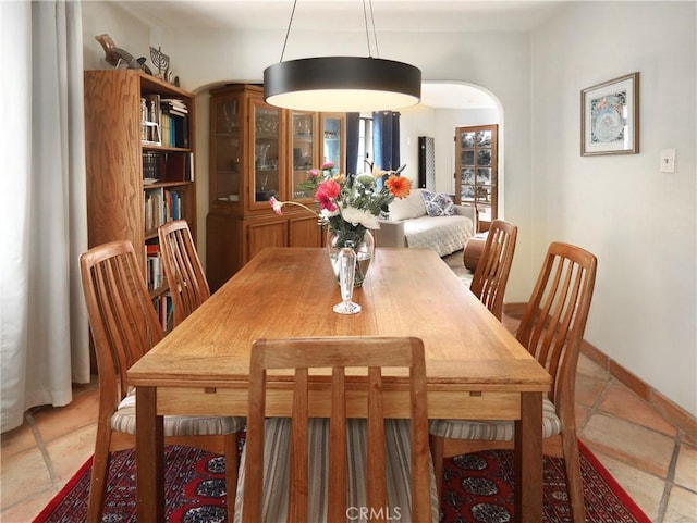 dining space featuring arched walkways and baseboards