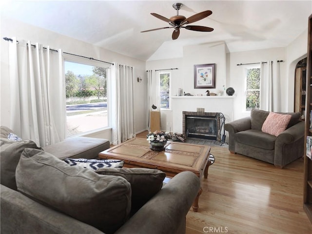 living room featuring wood finished floors, a fireplace with flush hearth, vaulted ceiling, and ceiling fan