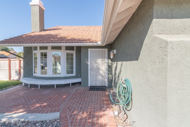 39203 Foxglove Cir, Murrieta, CA 92563 - view of exterior entry featuring a patio, a chimney, stucco siding, and fence