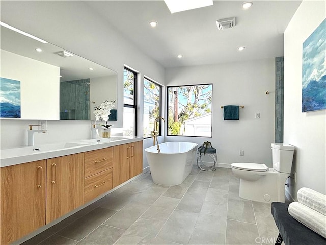 bathroom featuring a sink, double vanity, visible vents, recessed lighting, and a freestanding tub