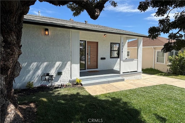rear view of house featuring a yard and stucco siding