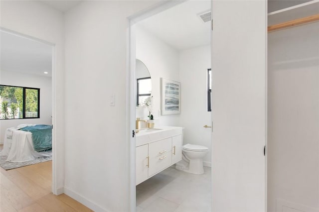 bathroom featuring toilet, vanity, baseboards, ensuite bath, and visible vents
