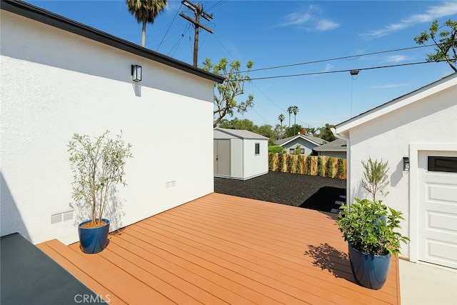 deck with a storage shed, fence, and an outdoor structure