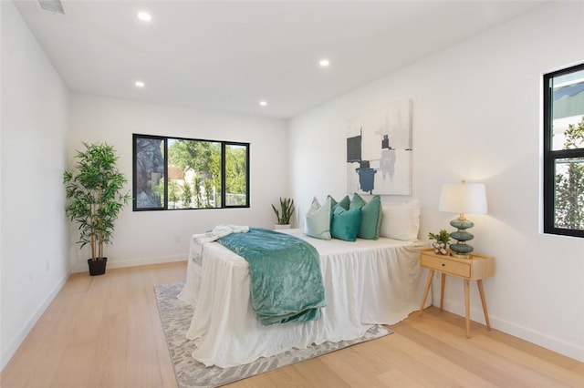 bedroom with baseboards, wood finished floors, multiple windows, and recessed lighting