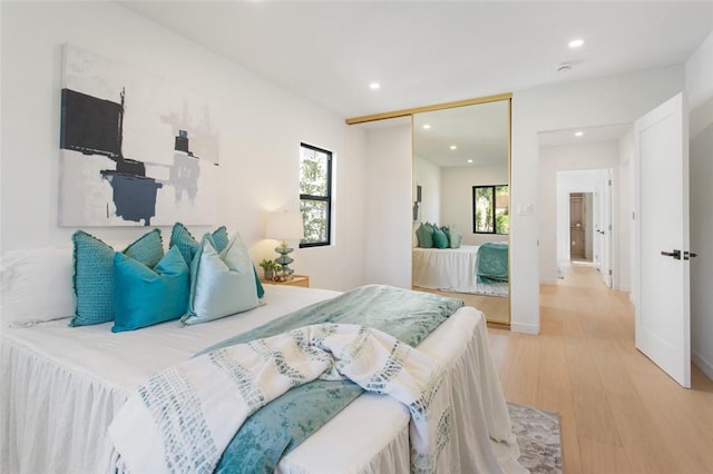 bedroom featuring baseboards, wood finished floors, recessed lighting, and a closet