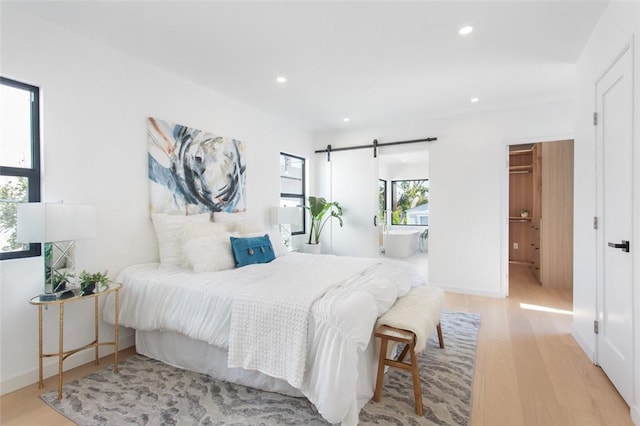 bedroom with baseboards, wood finished floors, recessed lighting, and a barn door