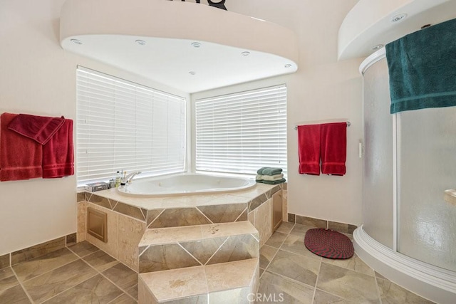 bathroom featuring tile patterned floors, baseboards, a garden tub, and a stall shower