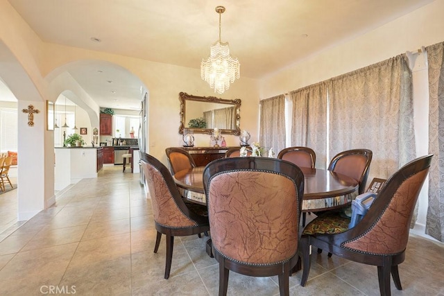 dining space with arched walkways, an inviting chandelier, and light tile patterned floors