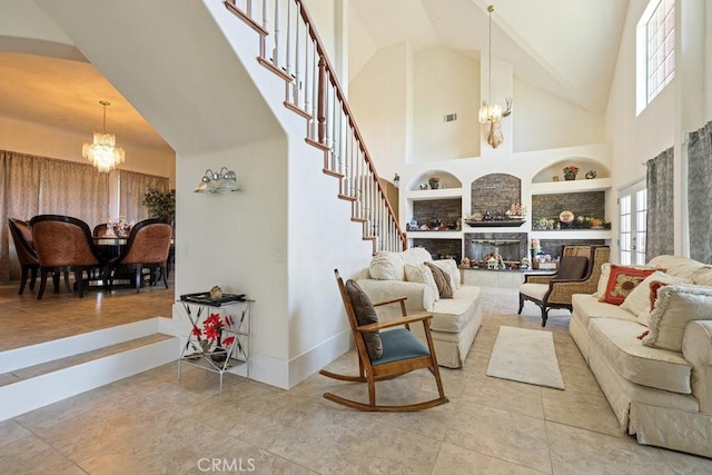 tiled living area with baseboards, built in features, a chandelier, stairs, and high vaulted ceiling