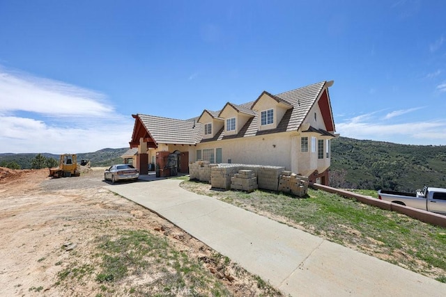 view of front of home featuring driveway, stucco siding, a mountain view, and a tile roof