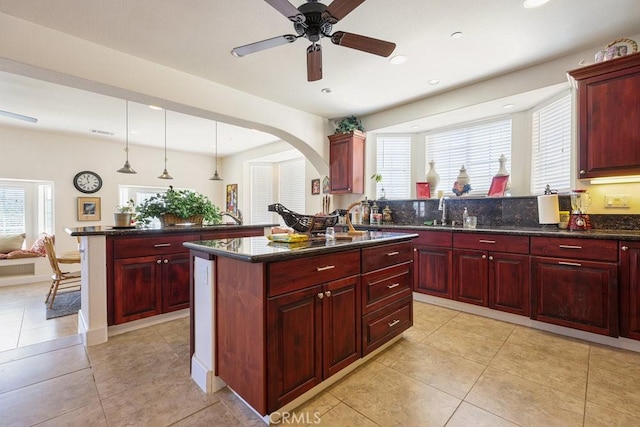 kitchen featuring reddish brown cabinets, a center island, a wealth of natural light, and a peninsula