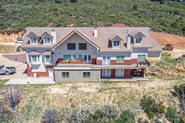 back of property featuring french doors, a forest view, and stucco siding