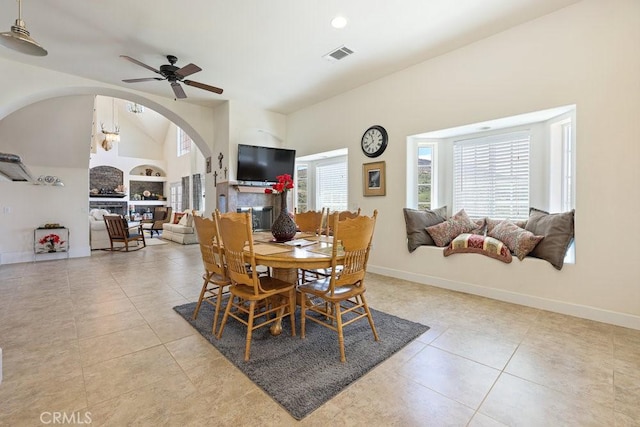dining room with visible vents, light tile patterned floors, baseboards, arched walkways, and ceiling fan