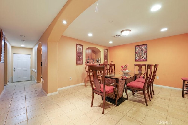 dining space featuring recessed lighting, arched walkways, and light tile patterned flooring