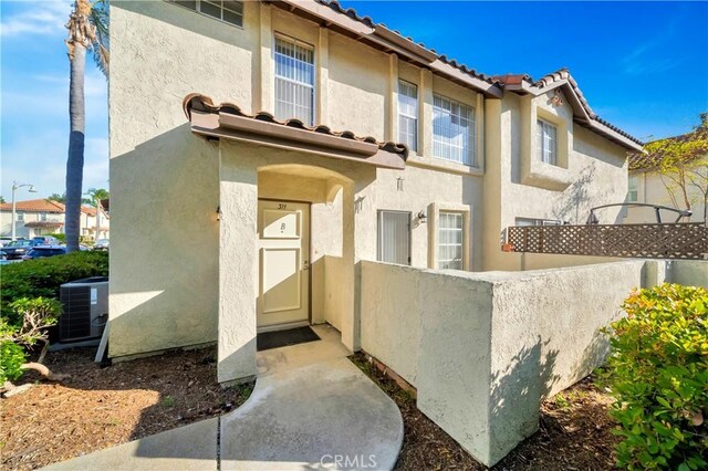 exterior space featuring a tile roof, stucco siding, cooling unit, and a fenced front yard