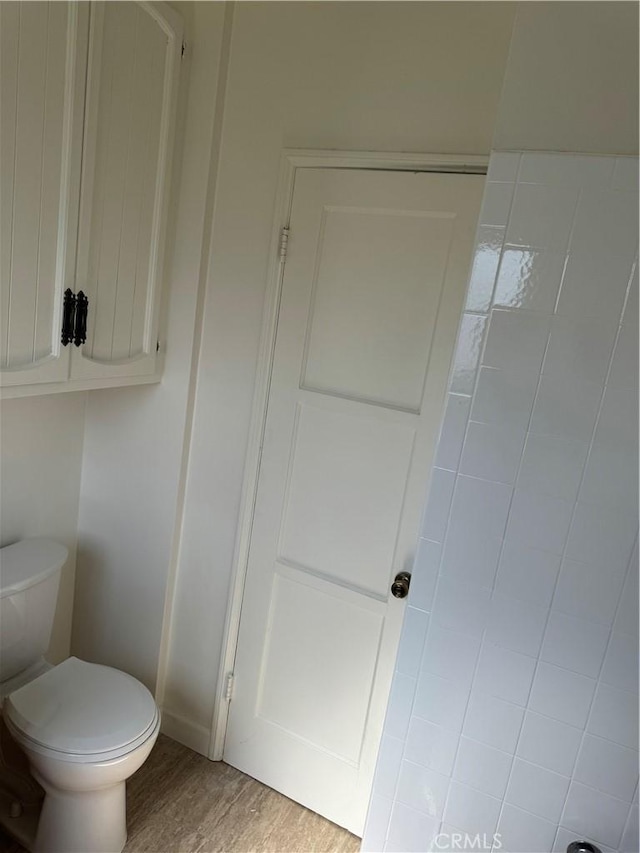bathroom with toilet, wood finished floors, and baseboards