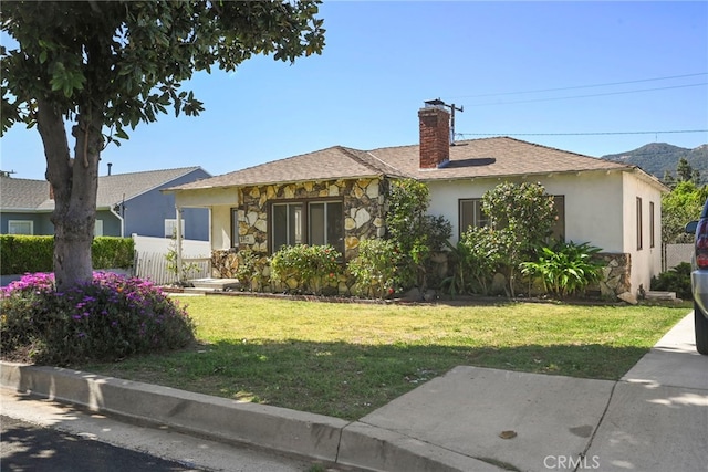 single story home featuring a chimney, fence, stone siding, and a front lawn