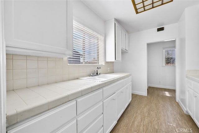 kitchen featuring white cabinets, baseboards, a sink, and decorative backsplash