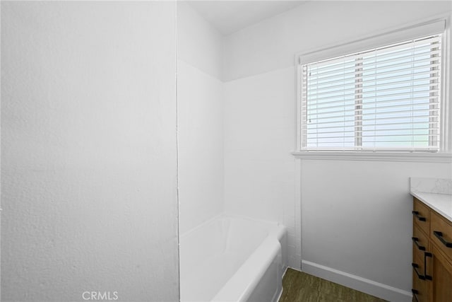 full bathroom featuring a wealth of natural light, vanity, wood finished floors, and baseboards