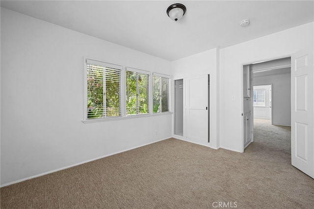 unfurnished bedroom with light colored carpet and baseboards