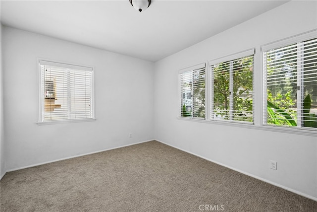 carpeted empty room featuring baseboards