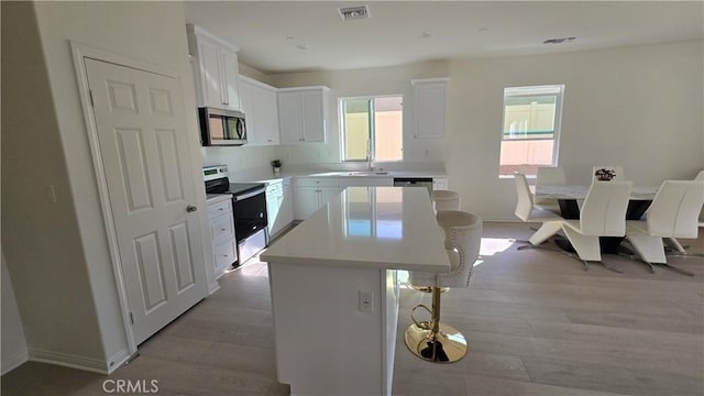 19427 Seeding Palace Cir, Riverside, CA 92507 - kitchen featuring appliances with stainless steel finishes, a center island, a kitchen bar, and healthy amount of natural light