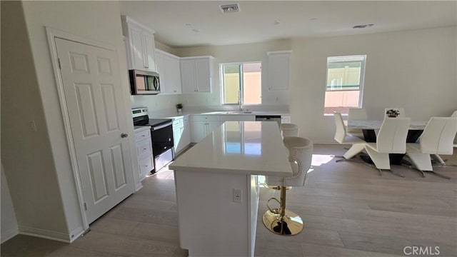 19427 Seeding Palace Cir, Riverside, CA 92507 - kitchen featuring stainless steel appliances, a kitchen island, a kitchen bar, and healthy amount of natural light