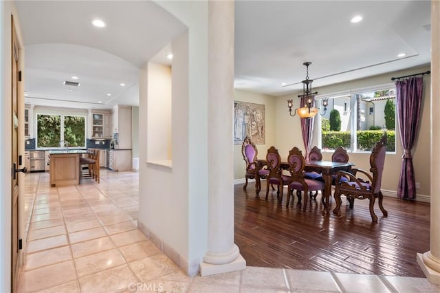 dining room with arched walkways, an inviting chandelier, baseboards, and recessed lighting