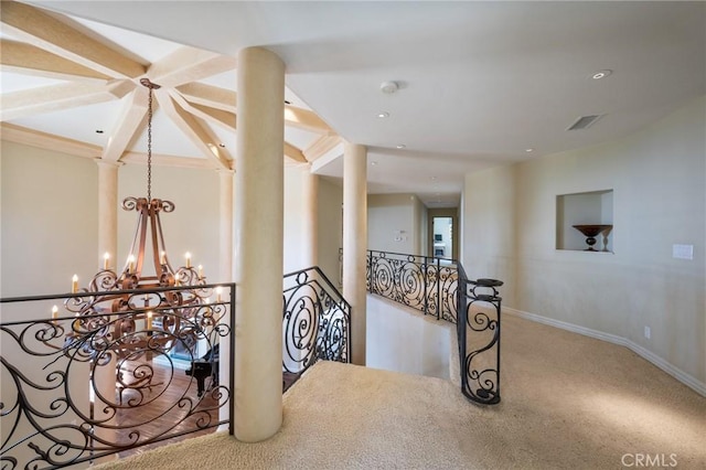 corridor with visible vents, baseboards, a notable chandelier, an upstairs landing, and carpet floors