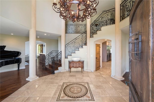 entrance foyer featuring a chandelier, arched walkways, a high ceiling, and stairs